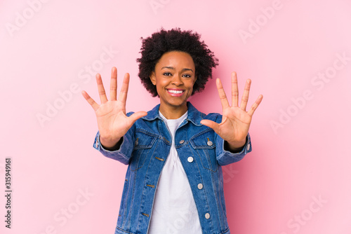 Young african american woman against a pink backgroound isolated showing number ten with hands.