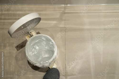 Foot opening a pedal bin which is empty seen from above with space for text