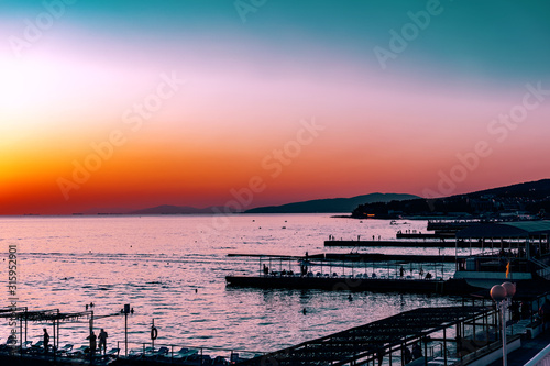 Красивый, красочный и контрастный закат над морем, океаном. Горячее солнце освещает просторный пейзаж, отбрасывая блики лучей на водную гладь. Яркий солнечный восход. Путешествие и туризм. © Анна Иванова