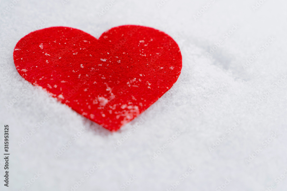 Love. Red heart in the snow close-up. 