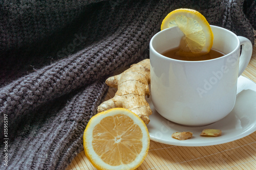 Cup of hot tea with ginger and sliced lemon on bamboo stand. Copy space