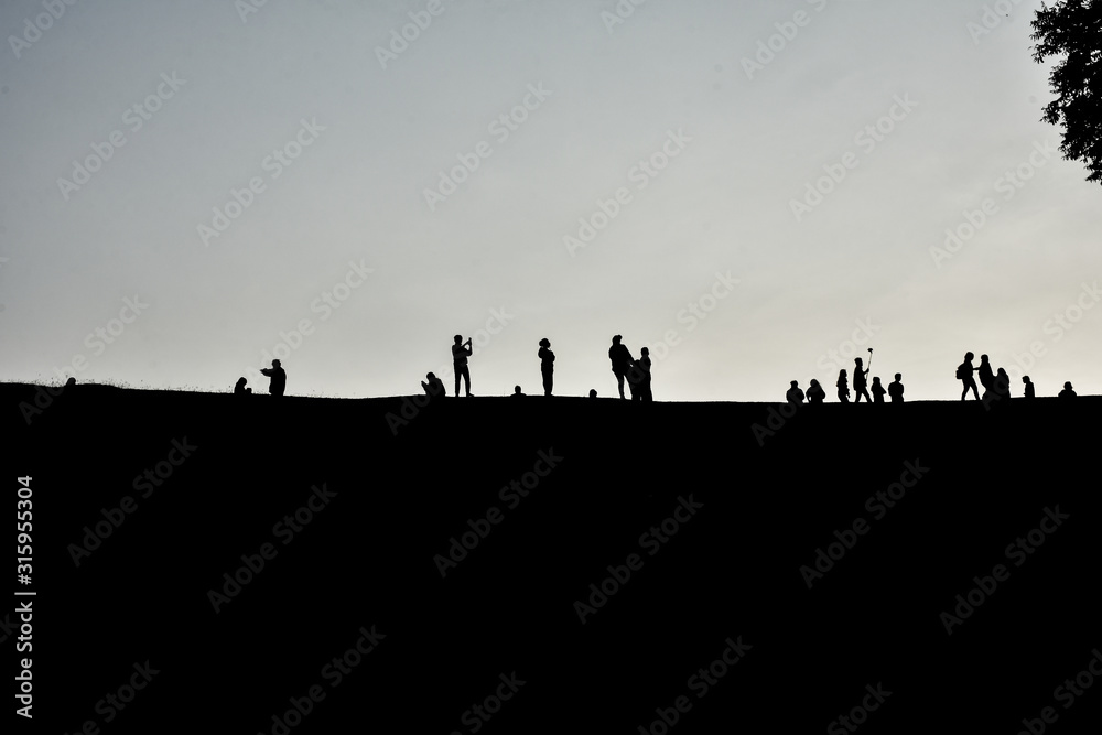 Silhouette of many people standing on the hill