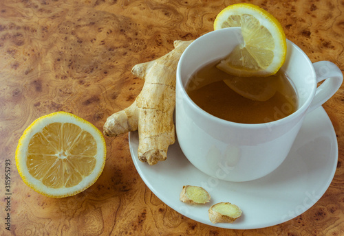 Cup of tea with ginger and sliced lemon on wooden background. Copy space