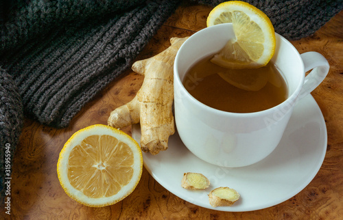 Top view of the cup of ginger tea with sliced lemon on wooden background.