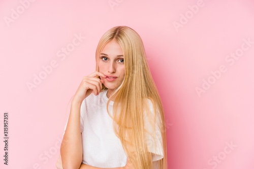 Young blonde woman face closeup isolated on a pink background