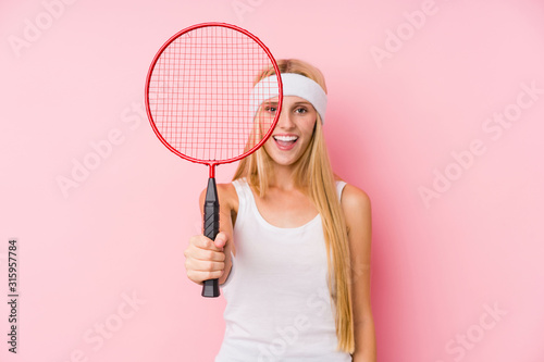 Young blonde woman playing badminton isolated
