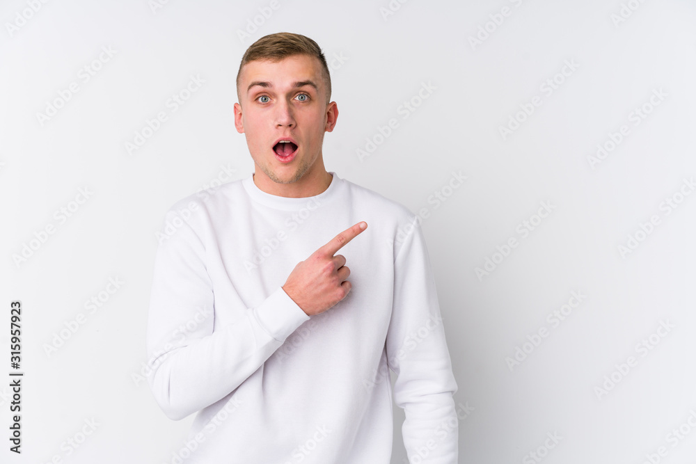 Young caucasian man on white background pointing to the side Young caucasian man on white background pointing to the side