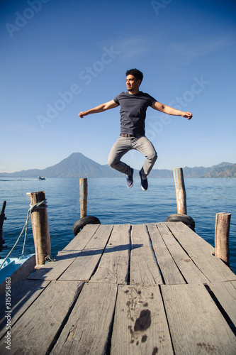 Young traveler jumping on the pier of Lake Atitlan in Guatemala - Young adventurer in Latin American tourist destination- young energetic at sunrise