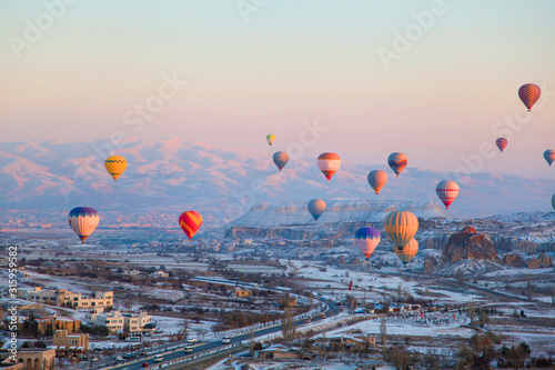 Colorful hot air balloons flying over the famous tourist place Cappadociaat at winter time
