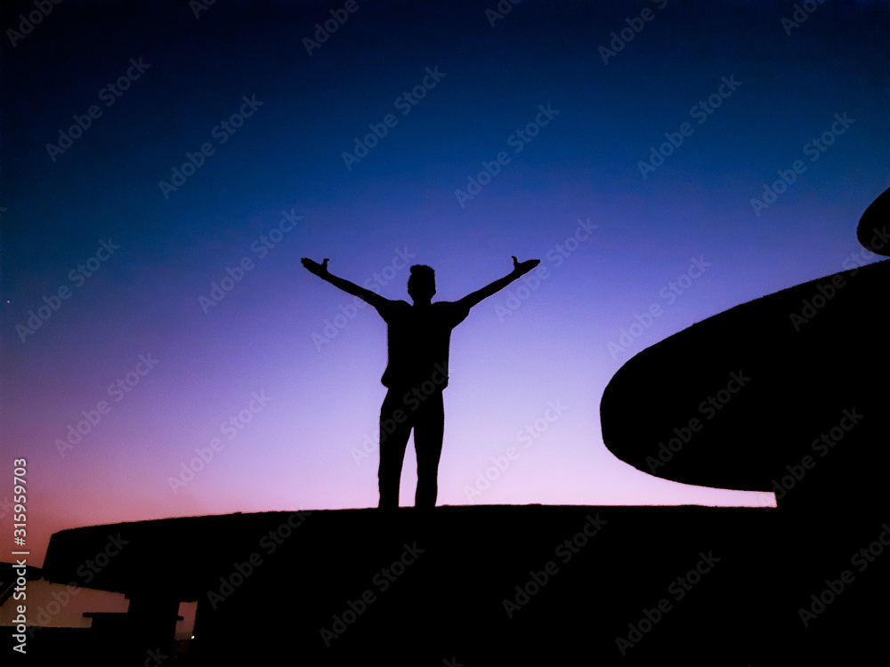 man with arms raised in the sky