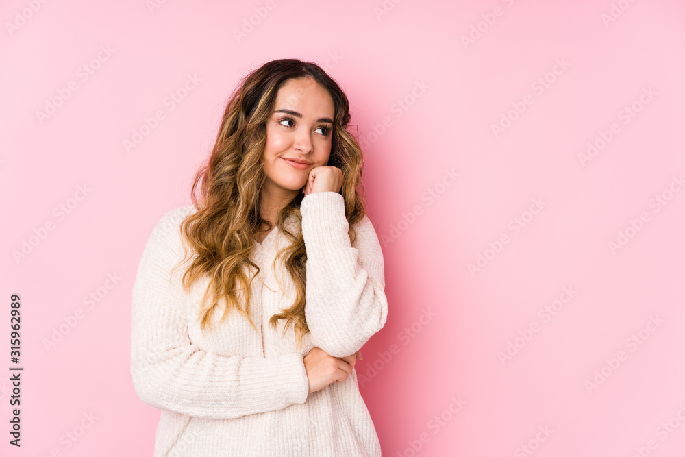 Young curvy woman posing in a pink background isolated who feels sad and pensive, looking at copy space. Young curvy woman posing in a pink background isolated who feels sad and pensive, looking at copy space.