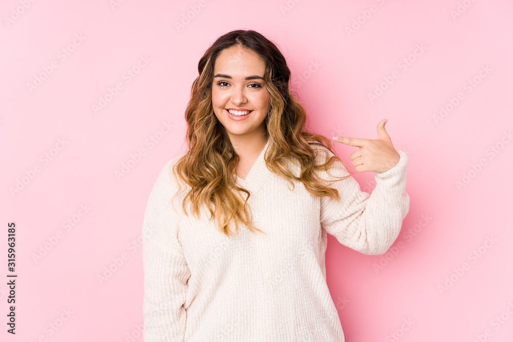 Young curvy woman posing in a pink background isolated person pointing by hand to a shirt copy space, proud and confident Young curvy woman posing in a pink background isolated person pointing by hand to a shirt copy space, proud and confident