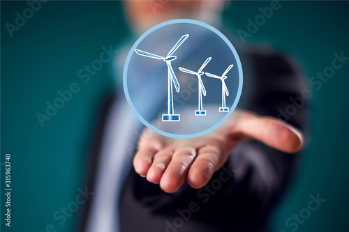 Businessman in suit showing open palm with virtual sign of wind generator. Alternative energy and environment ptotection concept