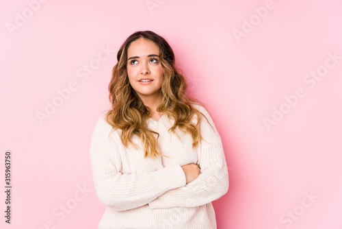 Young curvy woman posing in a pink background isolated tired of a repetitive task.