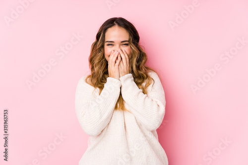 Fototapeta Young curvy woman posing in a pink background isolated laughing about something, covering mouth with hands