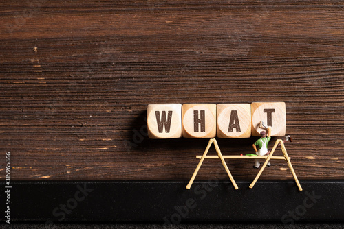 Fotografia painter figure and cubes with the word WHAT on wooden background