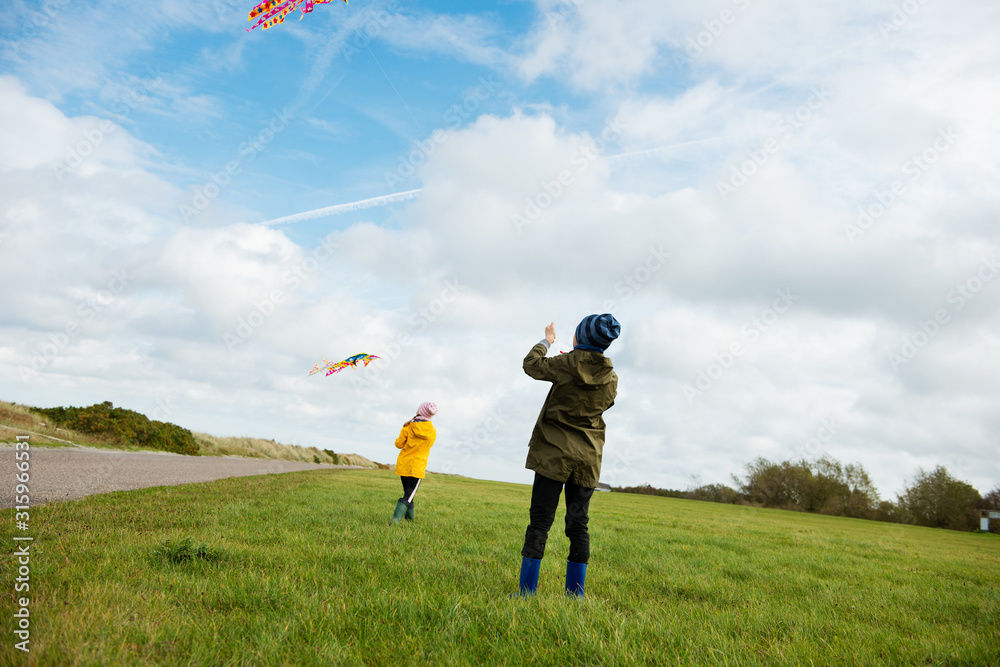Happy siblings children running and having fun with kite on beach Happy siblings children running and having fun with kite on beach