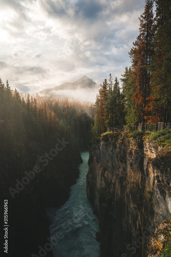 Fototapeta Naklejka Na Ścianę i Meble -  Stunning Sunrise with mist covering the mountains and River in the forest in Banff National Park in the Canadian Rockies