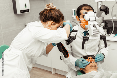 Two dentists treat a patient. Professional uniform and equipment of a dentist. Healthcare Equipping a doctor   s workplace. Dentistry