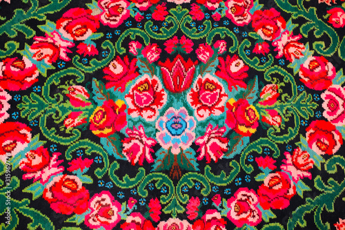 Colorful traditional vintage handmade folk carpet with floral shapes and motifs of Moldovian or Romanian traditions.