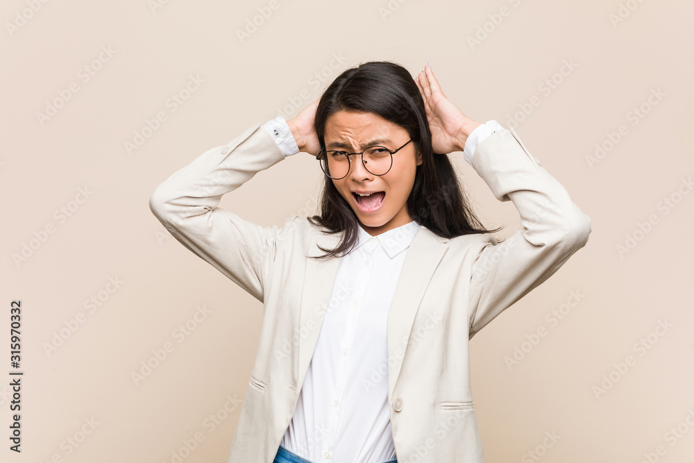 Young business chinese woman covering ears with hands trying not to hear too loud sound. Young business chinese woman covering ears with hands trying not to hear too loud sound.
