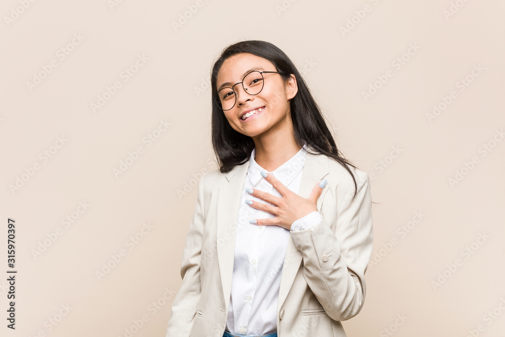 Young business chinese woman laughs out loudly keeping hand on chest. Young business chinese woman laughs out loudly keeping hand on chest.