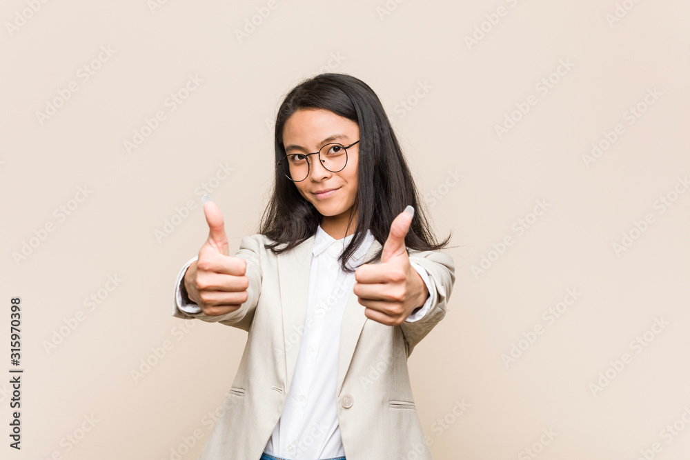 Young business chinese woman with thumbs ups, cheers about something, support and respect concept. Young business chinese woman with thumbs ups, cheers about something, support and respect concept.