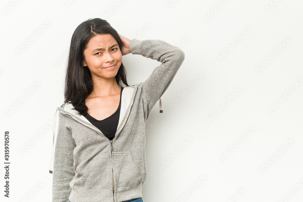 Young fitness chinese woman touching back of head, thinking and making a choice. Young fitness chinese woman touching back of head, thinking and making a choice.