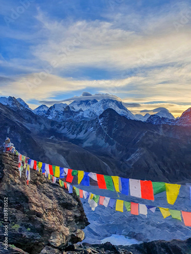 Picturesque view on Everest, Nuptse, Cholatse mountains and buddhist colorful praying flags. At the top of Gokyo Ri at sunrise. Trekking in Solokhumbu, Nepal, Himalayas.