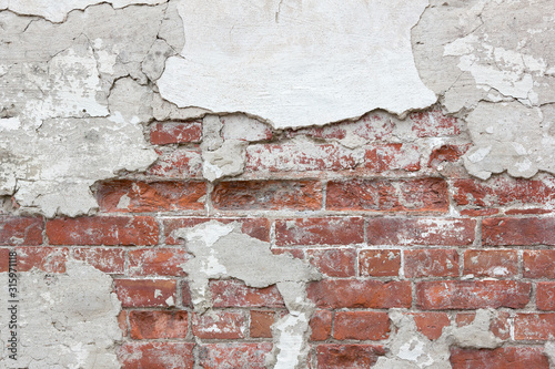 Texture of an old brick wall with fallen plaster. Background of a shabby building surface