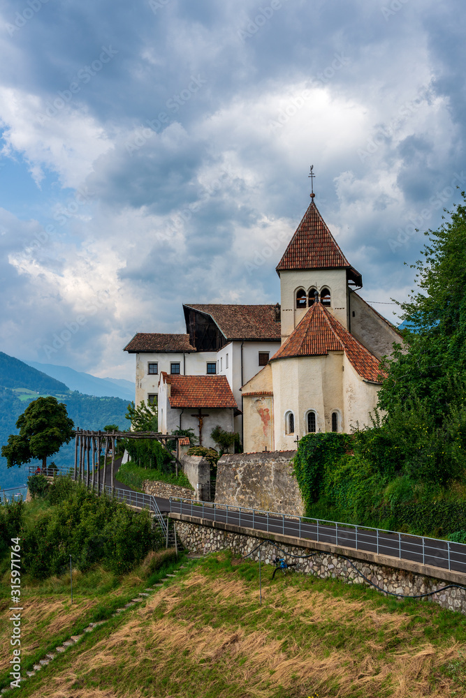 Thunderstorm clouds over the Parish Church of St. Peter in Tirol, South Tyrol. Italy.