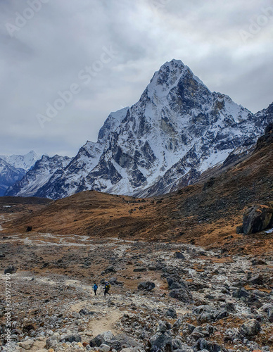 Trekkers heading to Dzongla. Fantastic Cholatse view. Everest base camp trek: from Dragnag to Dzongla via Cho La pass. Trekking in Solokhumbu, Nepal.