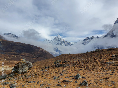 View on Ama Dablan in clouds from Dzongla village. Everest base camp trek: from Dragnag to Dzongla via Cho La pass. Trekking in Solokhumbu, Nepal. photo
