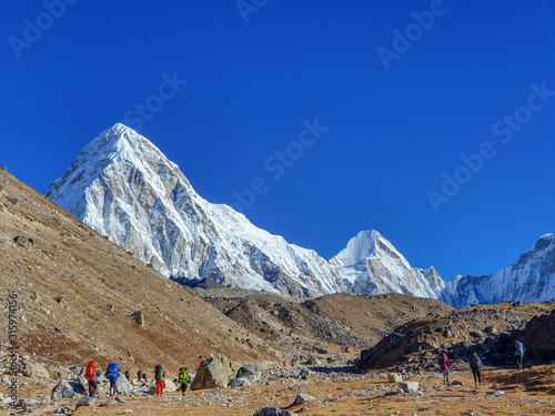 Early morning view on Pumori. Trekkers heading to Gorak Shep. Everest base camp trek: from Lobuche to Gorak Shep, Nepal, Himalayas. photo