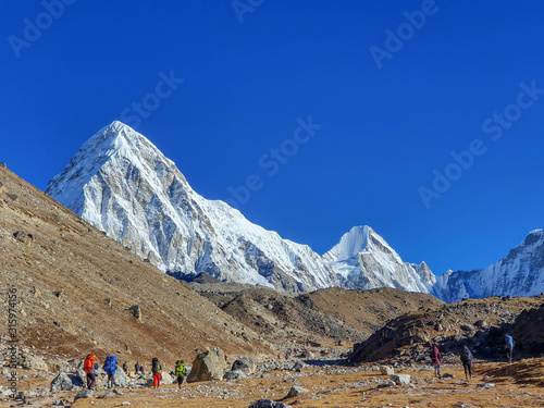 Early morning view on Pumori. Trekkers heading to Gorak Shep. Everest base camp trek: from Lobuche to Gorak Shep, Nepal, Himalayas.