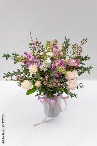 Gorgeous flower arrangement in a vase on a light background  color  white  pink  green. Flowers  rose  anemone  pistachio leaves 