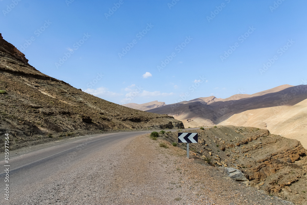 Empty road in southern Morocco with blue skies and mountains in the background Empty road in southern Morocco with blue skies and mountains in the background