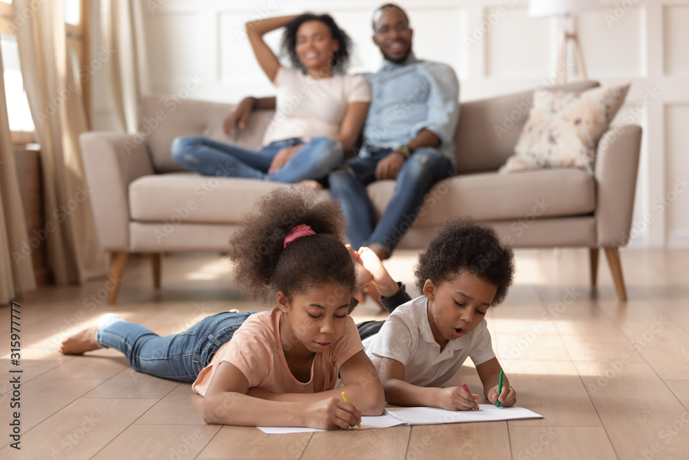 Mixed race brother and sister coloring pictures, lying on floor. Mixed race brother and sister coloring pictures, lying on floor.