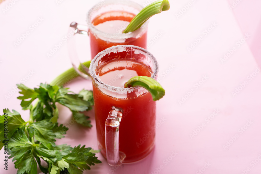 Mexican beer cocktail called michelada with celery on pink background Mexican beer cocktail called michelada with celery on pink background