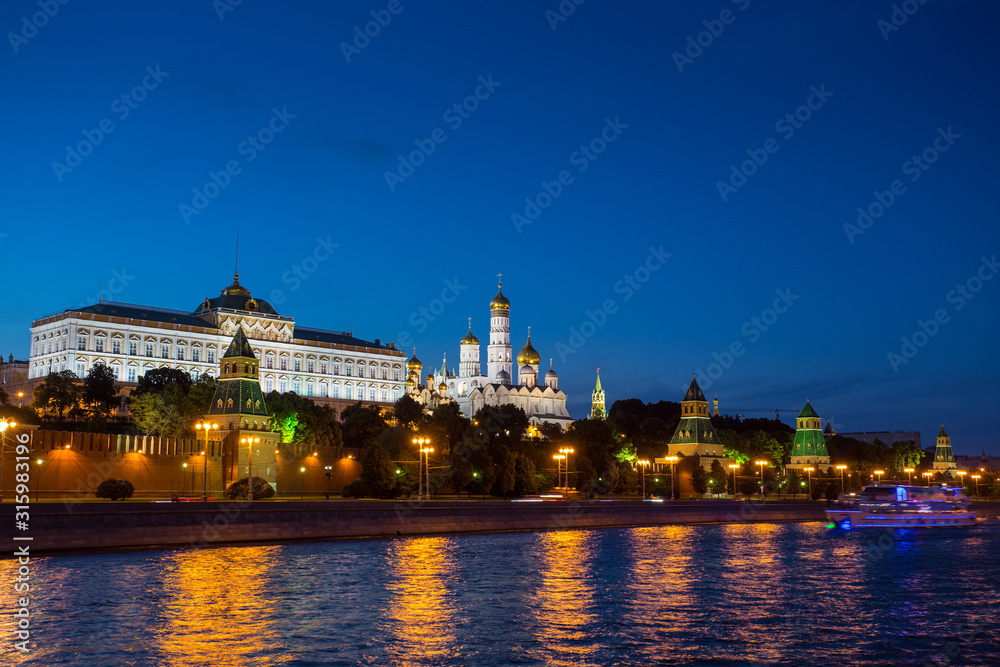 Moscow Kremlin at sunset with backlight on. View of the wall and temples from behind the river.