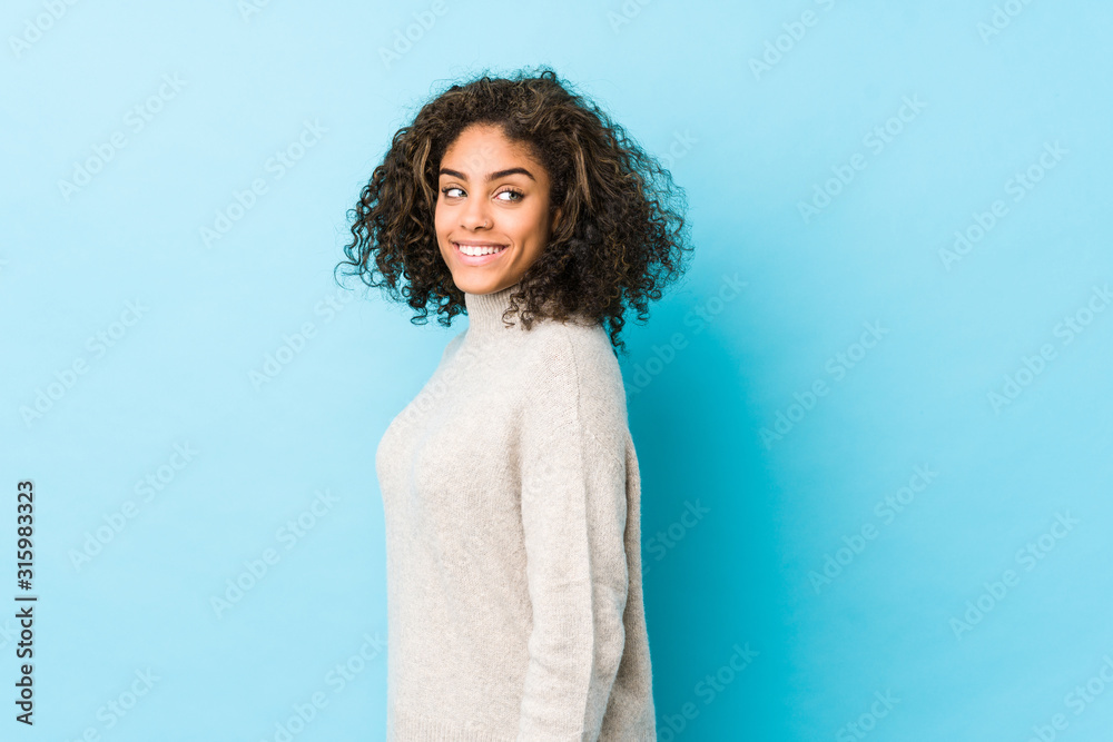 Fototapeta premium Young african american curly hair woman looks aside smiling, cheerful and pleasant.