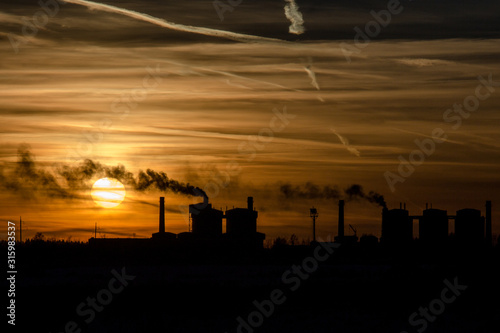 Sunset on the background of a plant with many smoking chimneys. Ecological problems.