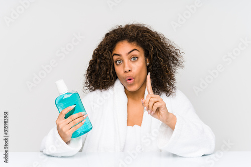 Young african american woman holding a mouth wash having some great idea, concept of creativity.