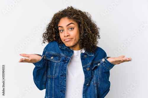 Young african american woman doubting and shrugging shoulders in questioning gesture.