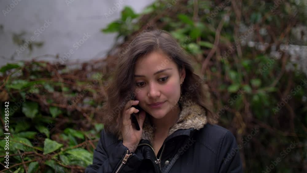 Smiling Young Mixed Woman talking on the Phone Outside with Winter Jacket on 4k Smiling Young Mixed Woman talking on the Phone Outside with Winter Jacket on 4k