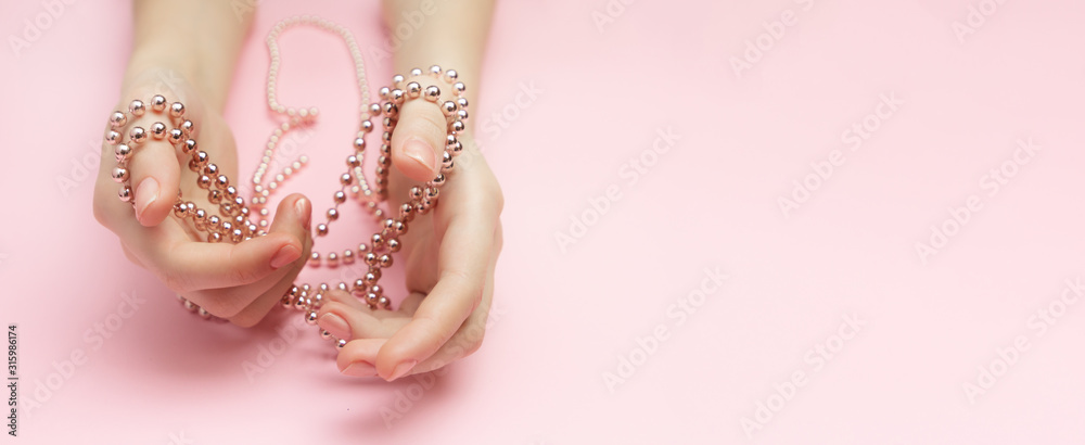 Fashion victim concept flat lay on a pink background. Shopaholics womens hands tied with a rope with beads. Compulsive buying disorder. Fashion victim concept flat lay on a pink background. Shopaholics womens hands tied with a rope with beads. Compulsive buying disorder.