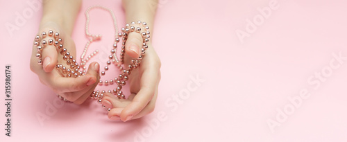 Fashion victim concept flat lay on a pink background. Shopaholics womens hands tied with a rope with beads. Compulsive buying disorder.
