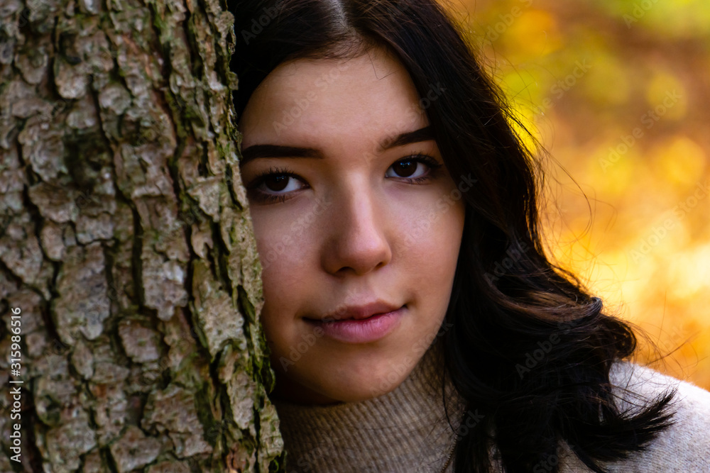 Portrait of a young pretty girl leaning her head against a tree trunk Portrait of a young pretty girl leaning her head against a tree trunk