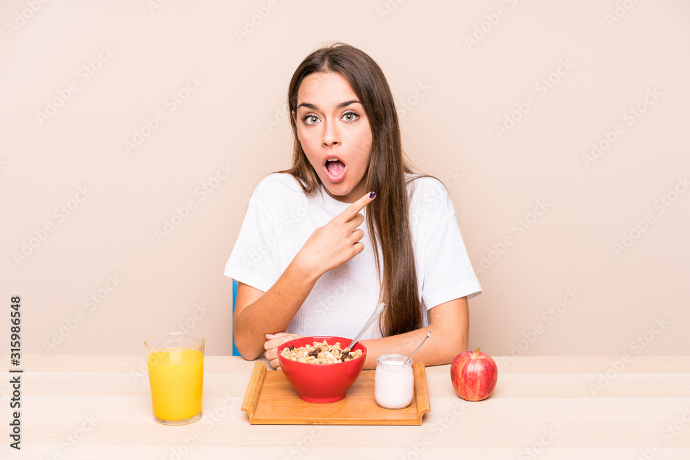 Young caucasian woman having a breakfast isolated pointing to the side Young caucasian woman having a breakfast isolated pointing to the side