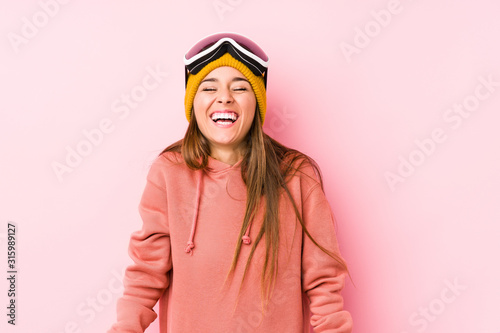 Young caucasian woman wearing a ski clothes isolated laughs and closes eyes, feels relaxed and happy.